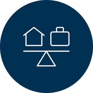 A blue circle icon with white outlines of a house and suitcase balanced on a seesaw, symbolizing work-life balance. The design conveys equilibrium.
